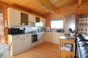 Une cuisine de taille réduite, dotée de meubles en bois, d’un four à micro-ondes, d’une cuisinière et d’un évier.