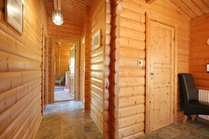 Un intérieur en bois avec un couloir menant à une porte, un radiateur et une chaise.