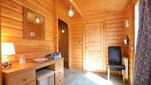 A wooden cabin interior with a desk, chair, and a door leading to another room. - Birchlea -  a lodge that sleeps 6 guests  in 3 bedrooms (Kippford, Dalbeattie)