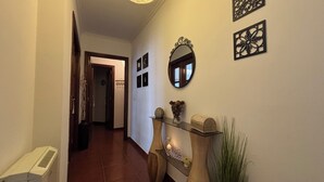 A hallway with a radiator, a mirror, wall art, and a plant.