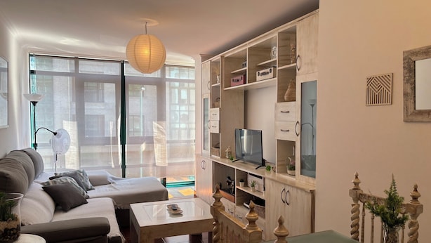 A living room with a sofa, a coffee table, a TV on a stand, and a bookshelf.