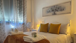 A neatly made bed with towels, a bedside lamp, and a wall-mounted artwork.