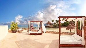 A beachside resort with a wooden canopy bed and a separate canopy bed, both with white linens, overlooking the ocean. - Cozumel Lively Studio with Pool & Gym (San Miguel de Cozumel)