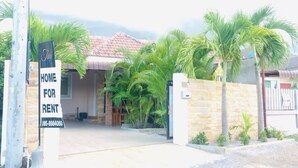 A house for rent with a tiled roof, a gated entrance, and a signboard. - Thai-scout Home (pran buri)