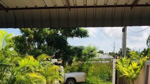 A covered parking area with a white pickup truck parked under a metal roof. - Thai-scout Home (pran buri)