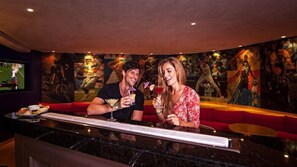 Una pareja sentada en un bar con un mural de temática deportiva al fondo.