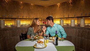 Una pareja cenando en un restaurante con una pared de piedra y un interior cálido e iluminado.