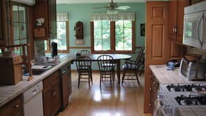 A kitchen with wooden cabinets, a dining table with chairs, a ceiling fan, and a stove. - 3 Bedroom House in Rural Setting but close to Iowa City/Solon (Solon)