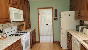 A kitchen with wooden cabinets, a white microwave, a stove, a refrigerator, and a dishwasher. - 3 Bedroom House in Rural Setting but close to Iowa City/Solon (Solon)