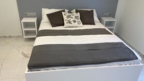 A modern bedroom with a white bed, dark and light striped bedding, and a decorative pillow. - Beautiful AqvaVilla in Poreč (Porec)