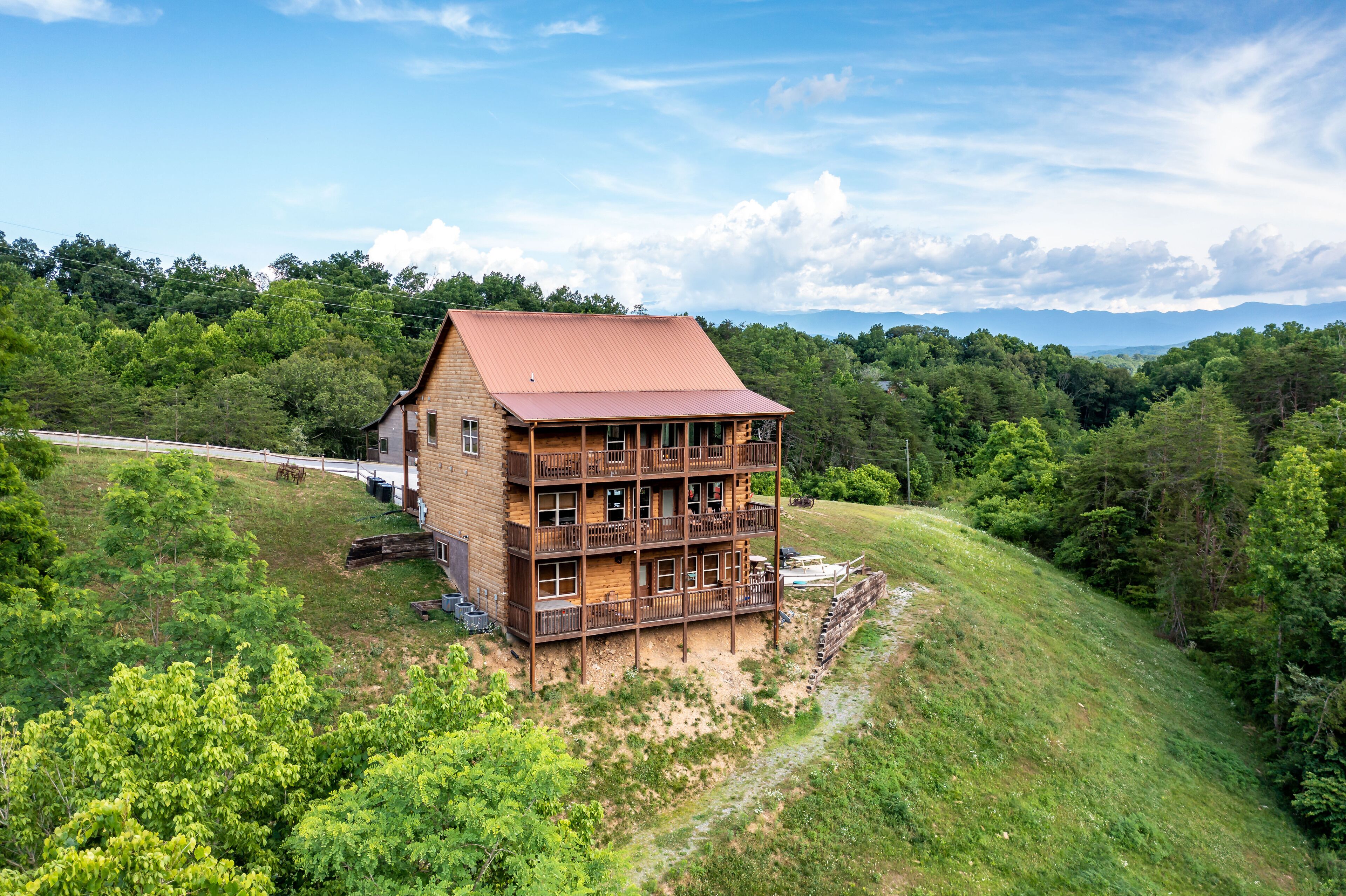 Eine mehrstöckige Holzhütte mit rotem Dach, umgeben von üppiger Vegetation und Hügeln.