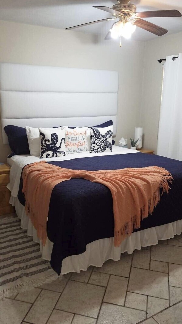A bedroom with a bed, pillows, a ceiling fan, and a nightstand. - Shell Yeah! 🐚 🏝 Paradise 🦀 (Son)