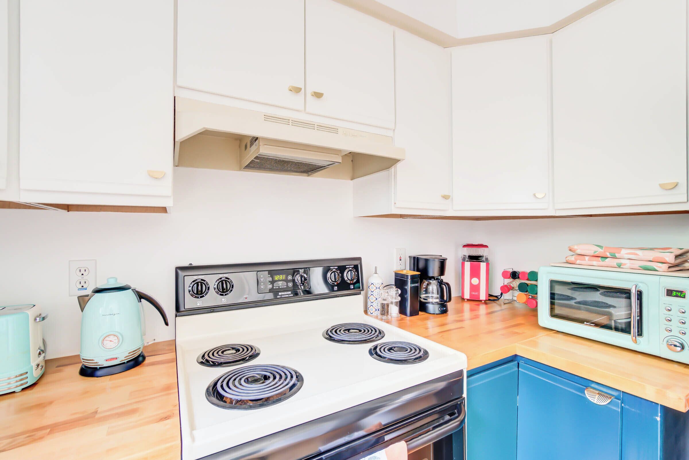 A kitchen with a white stove, a blue cabinet, and a microwave.
