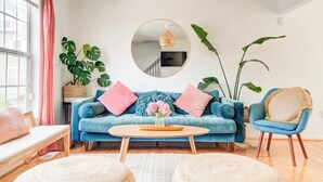 Ein Wohnzimmer mit einem blauen Sofa, einem runden Spiegel und einem Couchtisch.
