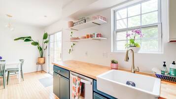 Una cocina moderna con encimeras de madera, un lavamanos empotrado y una ventana con vistas al verdor.