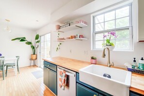A modern kitchen with wooden countertops, a built-in sink, and a window with a view of greenery.