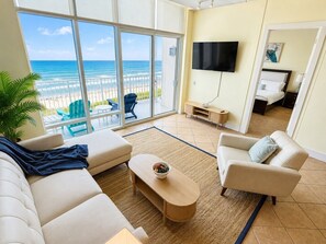 A living room with a sofa, armchair, coffee table, and a TV on the wall. - Sapphire 1906 - By GISO Vacation Rentals (South Padre Island)