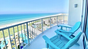 Un balcon avec deux fauteuils Adirondack bleus, une piscine et une vue sur la plage et l’océan.