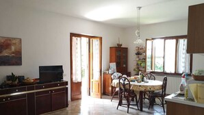 Une cuisine spacieuse comprenant une table à manger, des chaises, un téléviseur et un meuble de rangement.