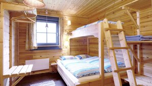 A wooden cabin room with bunk beds, a window with curtains, a desk, and a hanging light fixture. - Mountain cabin Ull Oviksfjällen, 4 people (Svenstavik)