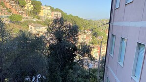 Un escalier menant à un immeuble d’où l’on a une vue sur une colline, avec des arbres et d’autres bâtiments.