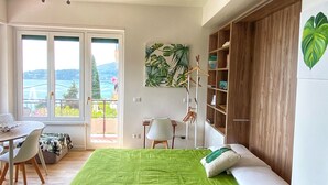 Une chambre à coucher comprenant un lit, un bureau, une chaise, une bibliothèque et une vue sur l’extérieur.