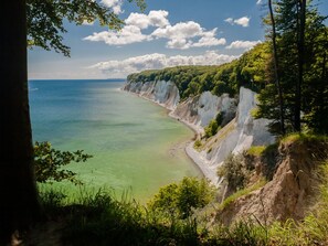 A coastal landscape with cliffs, a beach, and a clear sky.