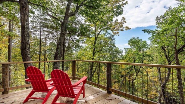 A wooden deck with two red Adirondack chairs overlooking a forested area. - Cozy, Seasonal Geo-Dome with Heat/AC on Private Wilderness Reserve in Gunks.  (Wallkill)