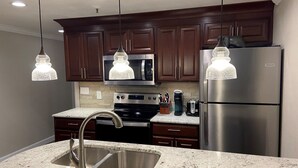 A modern kitchen with dark wooden cabinets, stainless steel appliances, and pendant lights. - Luxury Ski-in/Ski-out 2 BR, Soaring Eagle 207 (Snowshoe)