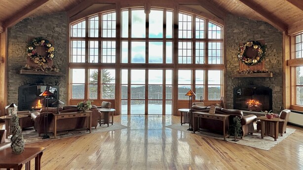 A spacious room with a high ceiling, large windows, a fireplace, and a stone wall. - Luxury Ski-in/Ski-out 2 BR, Soaring Eagle 207 (Snowshoe)