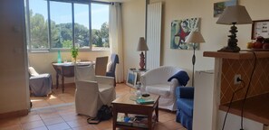 A living room with a sofa, chairs, a coffee table, and a dining area with a table and chairs. - Cosy Duplex Avec vue mer (Saint-Raphaël)
