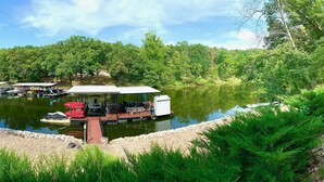 A dock with a covered seating area and a small boat. - 3 bedroom waterfront home Large dock and great swim area 4 KAYAKS + PADDLEBOAT (Sunrise Beach)
