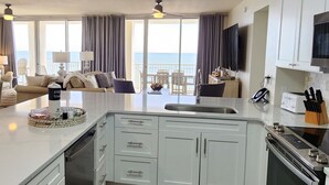 Una cocina moderna con armarios blancos, una isla central y vista al océano.