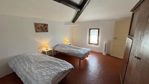 A room with two beds, a window, a heater, and a door. - Paul à 12 km de la mer (ROQUEBRUNE SUR ARGENS)