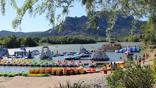 A lakeside area with boats and rafts, a sandy beach, and people. - Paul à 12 km de la mer (ROQUEBRUNE SUR ARGENS)