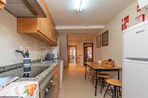A kitchen with a stove, sink, and wooden cabinets. There is a dining area with a table and chairs.
