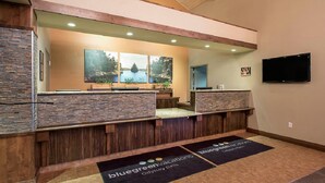 A reception area with stone counters, a large window with a scenic view, and a mounted television. - Mt. Olympus Water & Theme Park (Wisconsin Dells)