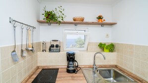A kitchen with a wooden countertop, a built-in stove, a coffee maker, a sink, and various utensils hanging on the wall. - Apartment Marija 5 mins away from Old Town (Dubrovnik)