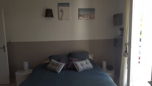 Un dormitorio con cama, almohadas, mesita de noche y decoración en la pared.