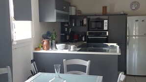 Una cocina moderna con una isla central, armarios blancos y un refrigerador de acero inoxidable.