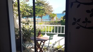 Una habitación con cama, una mesa y vistas a un balcón con mobiliario exterior y plantas.