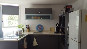 Una cocina moderna con armarios oscuros, un refrigerador blanco y una cafetera.