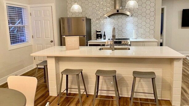 Een moderne keuken met een groot eiland, roestvrijstalen apparatuur en een backsplash van hexagontegels.