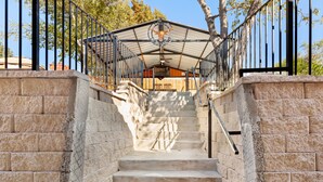 A set of stone steps leading up to a covered area with a metal railing and a hanging light fixture.