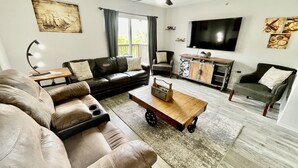 A living room with a sectional sofa, a coffee table, a TV, and a ceiling fan. - Accommodates 16! Stylish & Chic! Swim at pool! Close to Lake, SDC & Hwy 76 Strip (Branson)