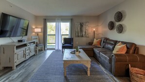 A living room with a television, a sofa, a coffee table, and a dining area. - Accommodates 16! Stylish & Chic! Swim at pool! Close to Lake, SDC & Hwy 76 Strip (Branson)