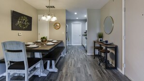A dining area with a wooden bench, a white chair, a chandelier, and a wall-mounted mirror. - Accommodates 16! Stylish & Chic! Swim at pool! Close to Lake, SDC & Hwy 76 Strip (Branson)