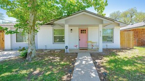 A single-story house with a pink front door, white exterior walls, and a small front yard. - 4BDR+Pets OK+Huge Yard+FirePit+3mintoBeach (Rockport)