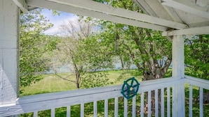A covered porch with a view of a grassy area and trees. - Beautiful River front property (Celina)