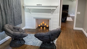 A room with a fireplace, two armchairs, a patterned rug, and a television in the background. - Beautiful River front property (Celina)